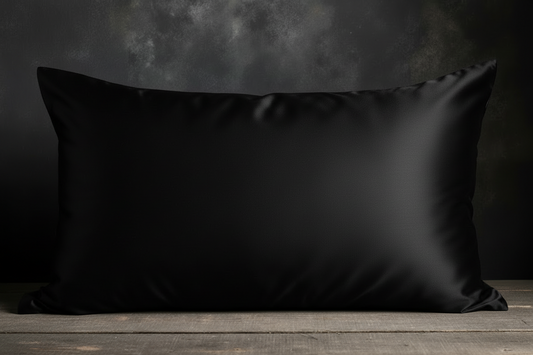 Black satin pillow on a wooden surface with a dark background